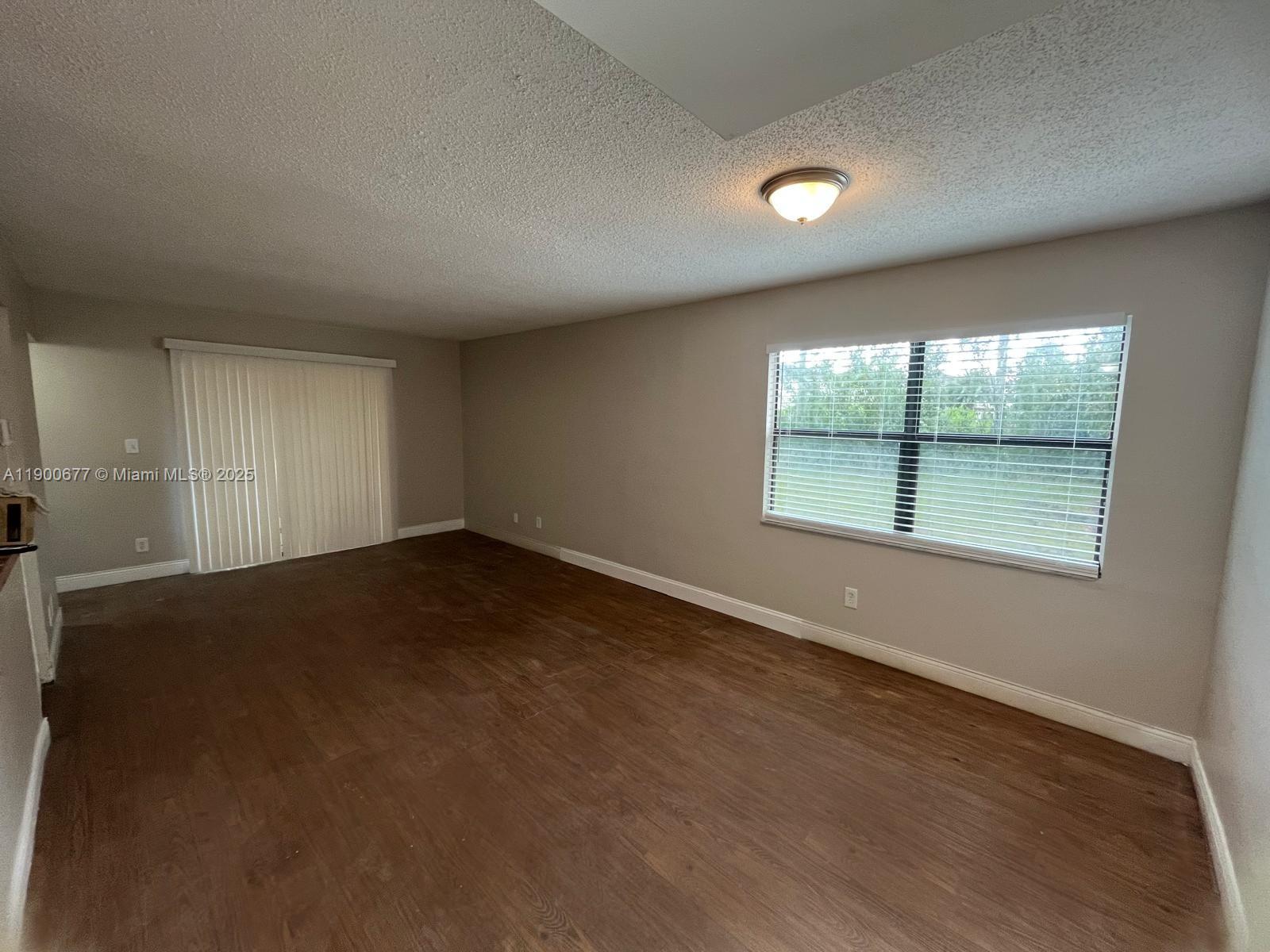 3400 Foxcroft Road, Unit 115 Miramar, FL 33025 - Photo 9 of 16 an empty room with wooden floor and windows