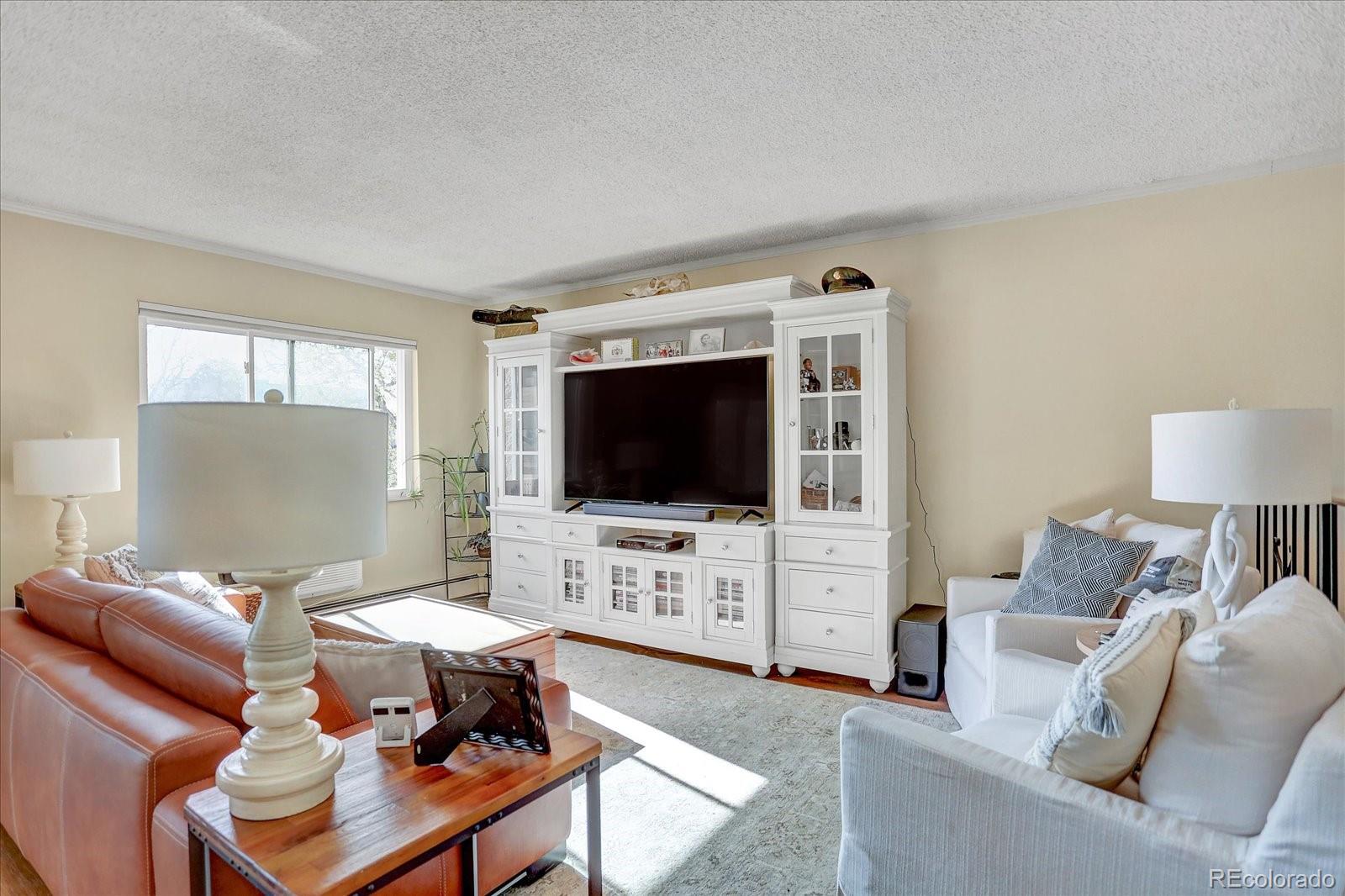 7040 East Girard Avenue, Unit E406 Denver, CO 80224 - Photo 8 of 27 a living room with furniture and a flat screen tv