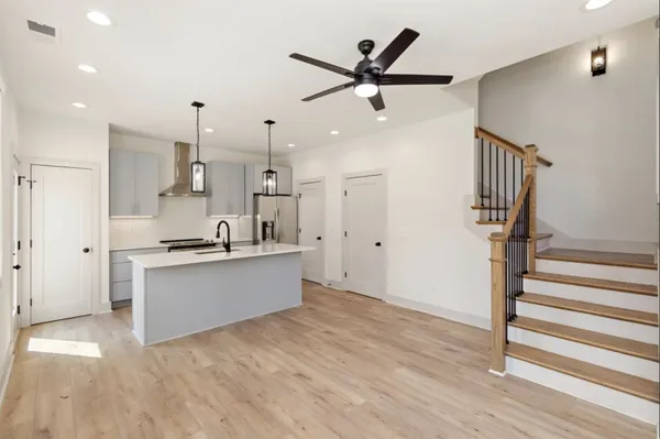 a kitchen with stainless steel appliances a refrigerator a sink and white cabinets