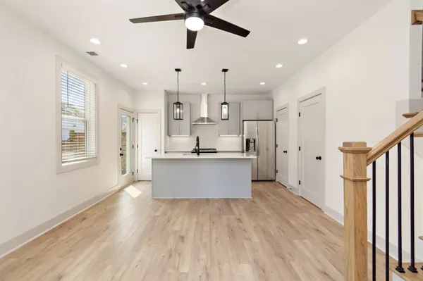 a large kitchen with stainless steel appliances kitchen island a large counter top and wooden floors