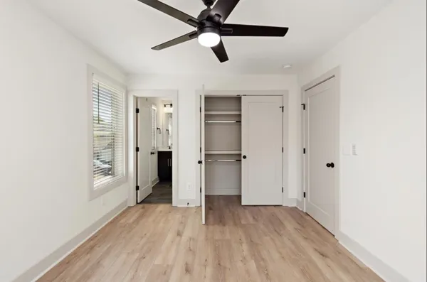 a view of empty room with wooden floor and fan