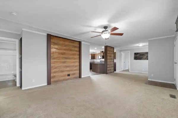 a view of an empty room with a ceiling fan and entryway