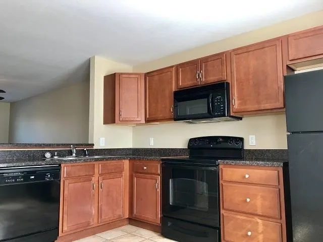 a kitchen with granite countertop a stove top oven microwave and cabinets