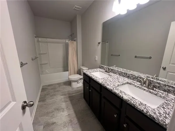 a bathroom with a granite countertop sink a toilet and shower