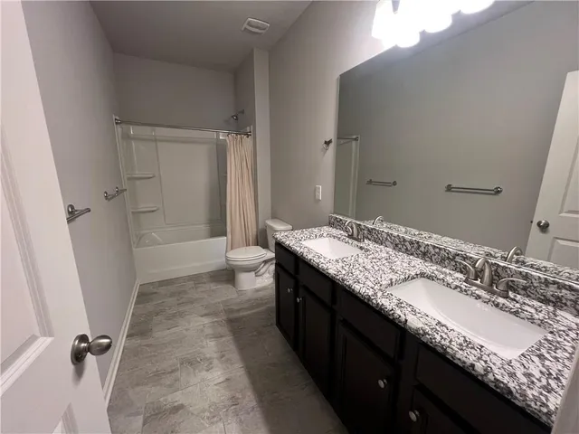 a bathroom with a granite countertop sink a toilet and shower