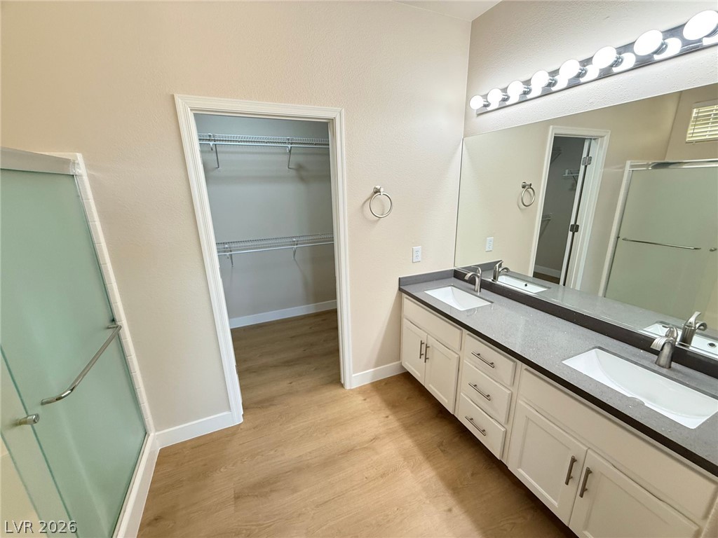 3036 Fort Stanwix Road Henderson, NV 89052 - Photo 17 of 18 An expansive double vanity and a nearby walk-in closet highlight this modern primary bathroom.