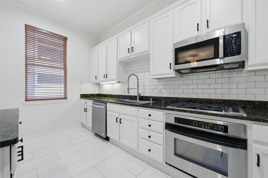 4330 McKinney Avenue, Unit 16 Dallas, TX 75205 - Photo 7 of 34 Crisp white cabinetry compliments the stainless steel appliances, granite countertops and recently installed subway tile. New microwave was installed in 2026.