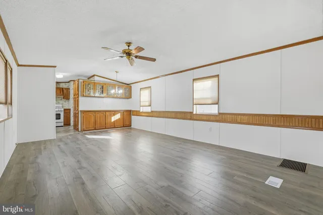 a view of empty room with wooden floor and fan