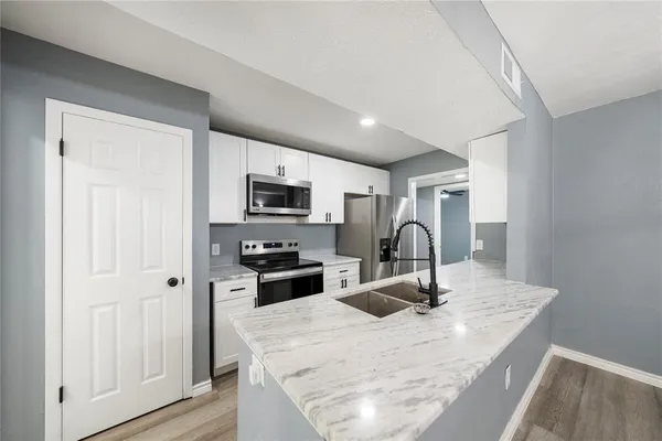 a kitchen with stainless steel appliances granite countertop a sink refrigerator stove and microwave