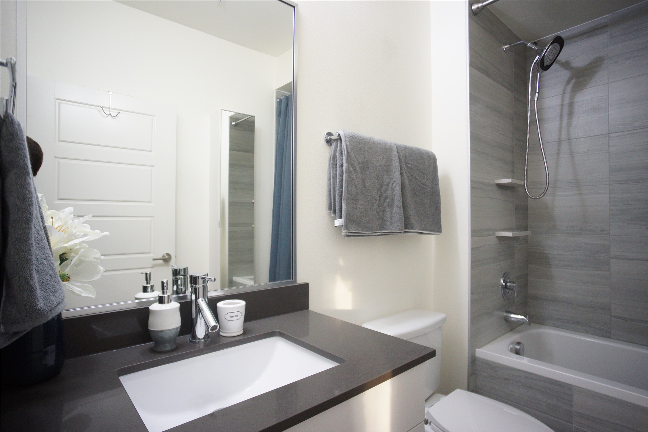 6444 Burnet Road, Unit 305 Austin, TX 78757 - Photo 11 of 15 Modern full bathroom with a sleek vanity, large mirror, and tiled tub/shower.