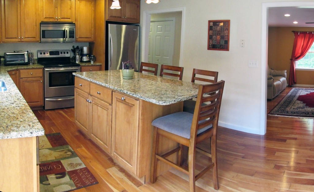 185 Burbank Road Sutton, MA 01590 - Photo 9 of 30 a kitchen with stainless steel appliances granite countertop a stove top oven a sink a dining table and chairs with wooden floor