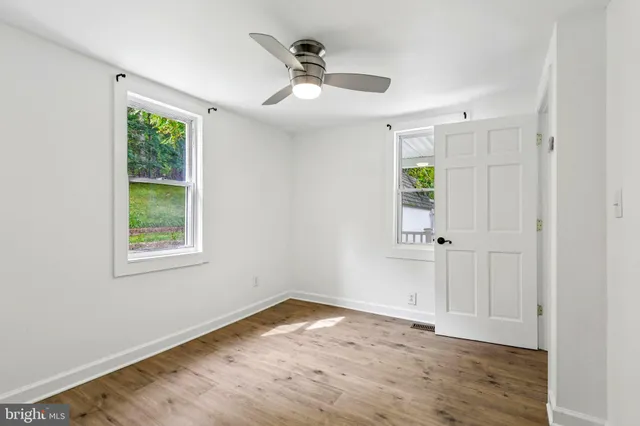 a view of empty room with wooden floor and fan