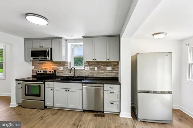 a kitchen with stainless steel appliances granite countertop a refrigerator a stove a sink and a microwave