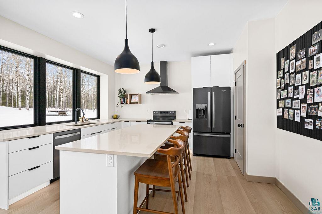 1491 Wildwood Road Duluth, MN 55804 - Photo 8 of 38 Kitchen featuring white cabinetry, black appliances, modern cabinets, a kitchen island, and a kitchen breakfast bar