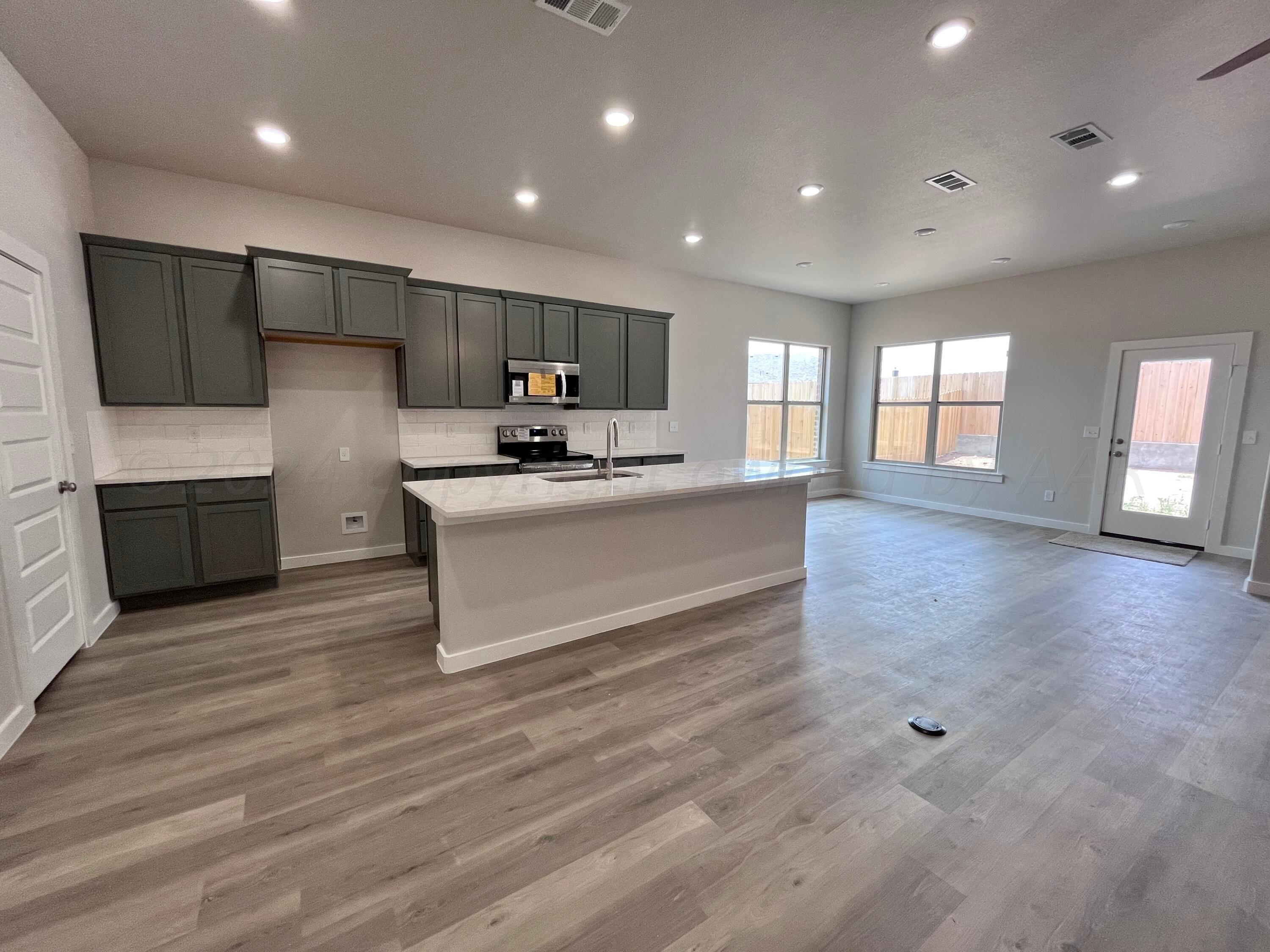 1605 Moon River Road Amarillo, TX 79118 - Photo 5 of 17 a large white kitchen with wooden floors and stainless steel appliances