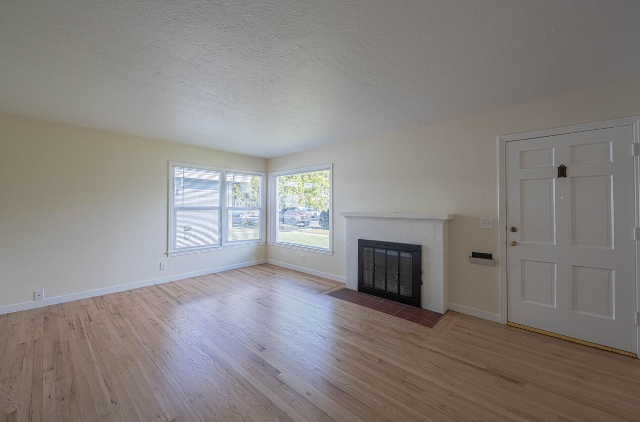 1221 Parkside Street Salinas, CA 93906 - Photo 6 of 41 an empty room with wooden floor fireplace and windows