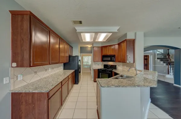 a kitchen with granite countertop a sink a counter top space cabinets and stainless steel appliances