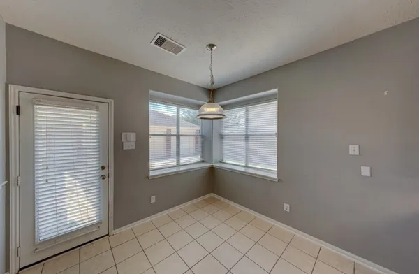 a view of an empty room with window and chandelier fan