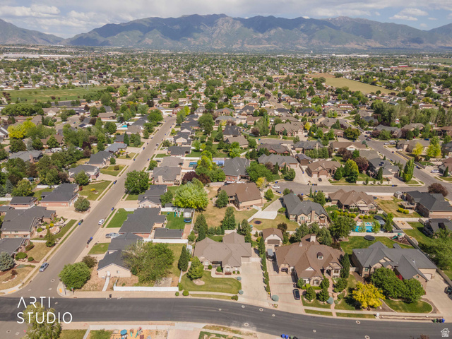 2327 Bluff Ridge Drive Syracuse, UT 84075 - Photo 62 of 66 Expansive residential area with a mountain backdrop, featuring numerous single-family homes, mature trees, paved streets, and a mixture of residential and undeveloped land