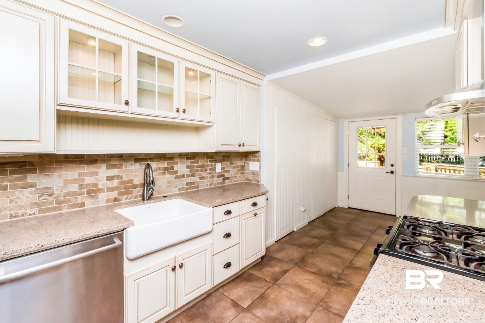 10 South Hathaway Road Mobile, AL 36608 - Photo 6 of 46 Kitchen with stainless steel dishwasher, glass insert cabinets, light stone countertops, black gas range oven, and backsplash