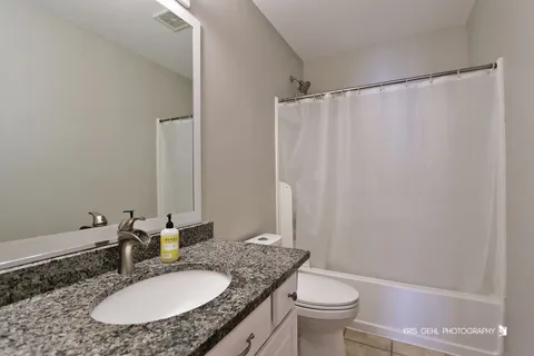 a bathroom with a granite countertop sink toilet and a mirror