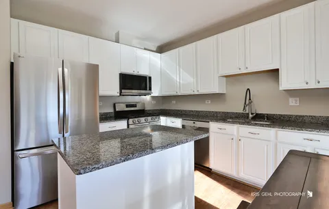 a kitchen with stainless steel appliances granite countertop a refrigerator a stove a sink a microwave and refrigerator