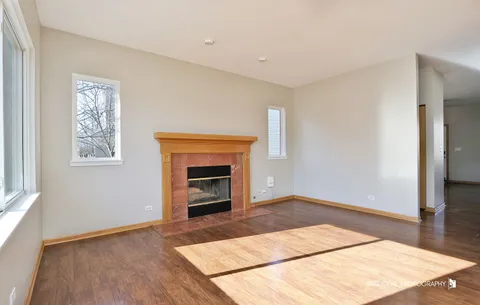 an empty room with windows and fireplace