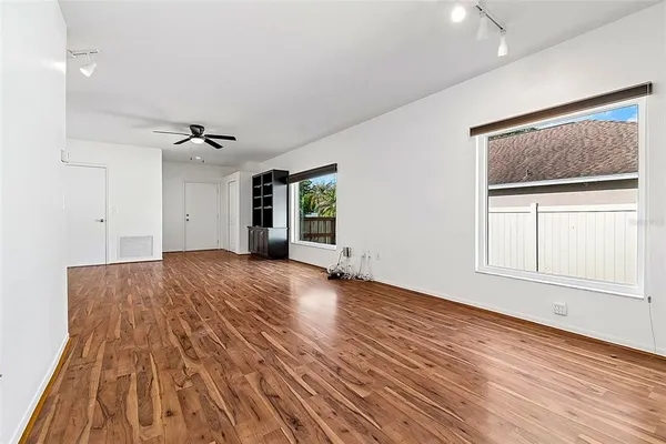a view of an empty room with wooden floor and a window