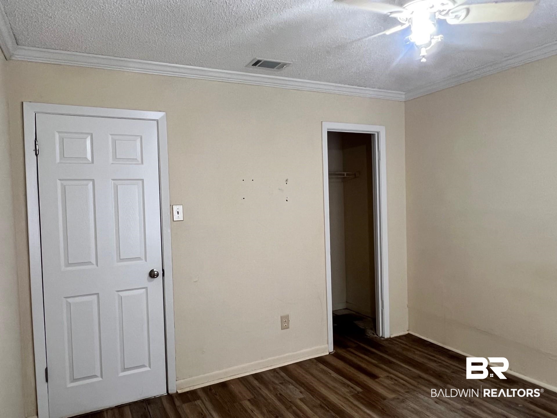 72 Grimes Lane Loxley, AL 36551 - Photo 9 of 12 Unfurnished bedroom featuring a textured ceiling, dark wood finished floors, ornamental molding, ceiling fan, and a walk in closet