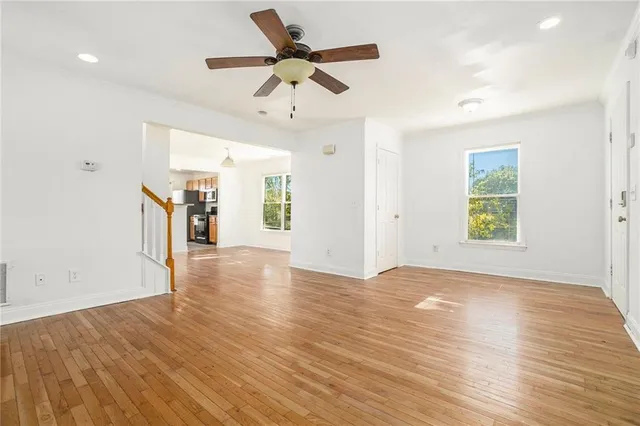 a view of empty room with wooden floor and ceiling fan
