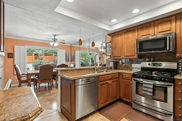 a kitchen with stainless steel appliances granite countertop a stove top oven a sink dishwasher a dining table and chairs with wooden floor