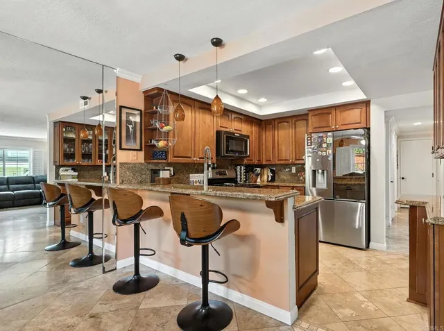 a kitchen with stainless steel appliances kitchen island granite countertop a refrigerator a stove and a sink