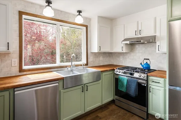 a kitchen with stainless steel appliances white cabinets and a stove top oven
