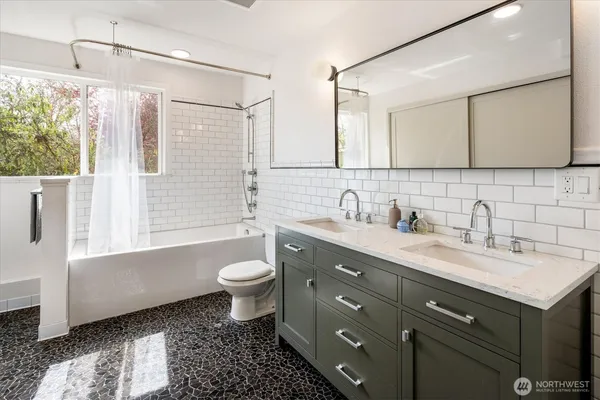 a bathroom with a double vanity sink toilet mirror and bathtub