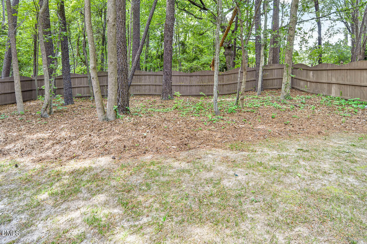 2209 Lodestar Drive Raleigh, NC 27615 - Photo 50 of 50 a backyard of a house with large trees and wooden fence