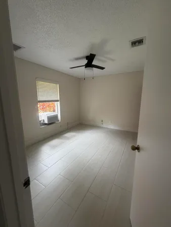 an empty room with windows and fan