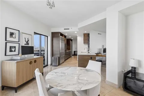 a large white kitchen with stainless steel appliances kitchen island a stove a refrigerator a oven a sink a dining table and chairs with wooden floor