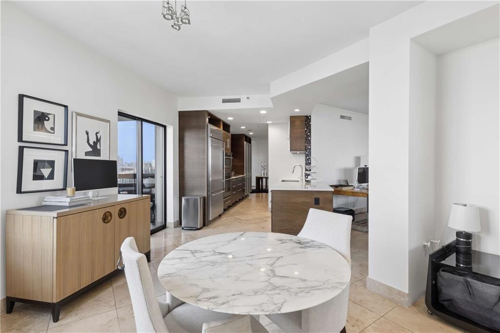 2660 Peachtree Road Northwest, Unit 39D Atlanta, GA 30305 - Photo 15 of 45 a large white kitchen with stainless steel appliances kitchen island a stove a refrigerator a oven a sink a dining table and chairs with wooden floor