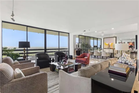 a living room with furniture kitchen view and a large window