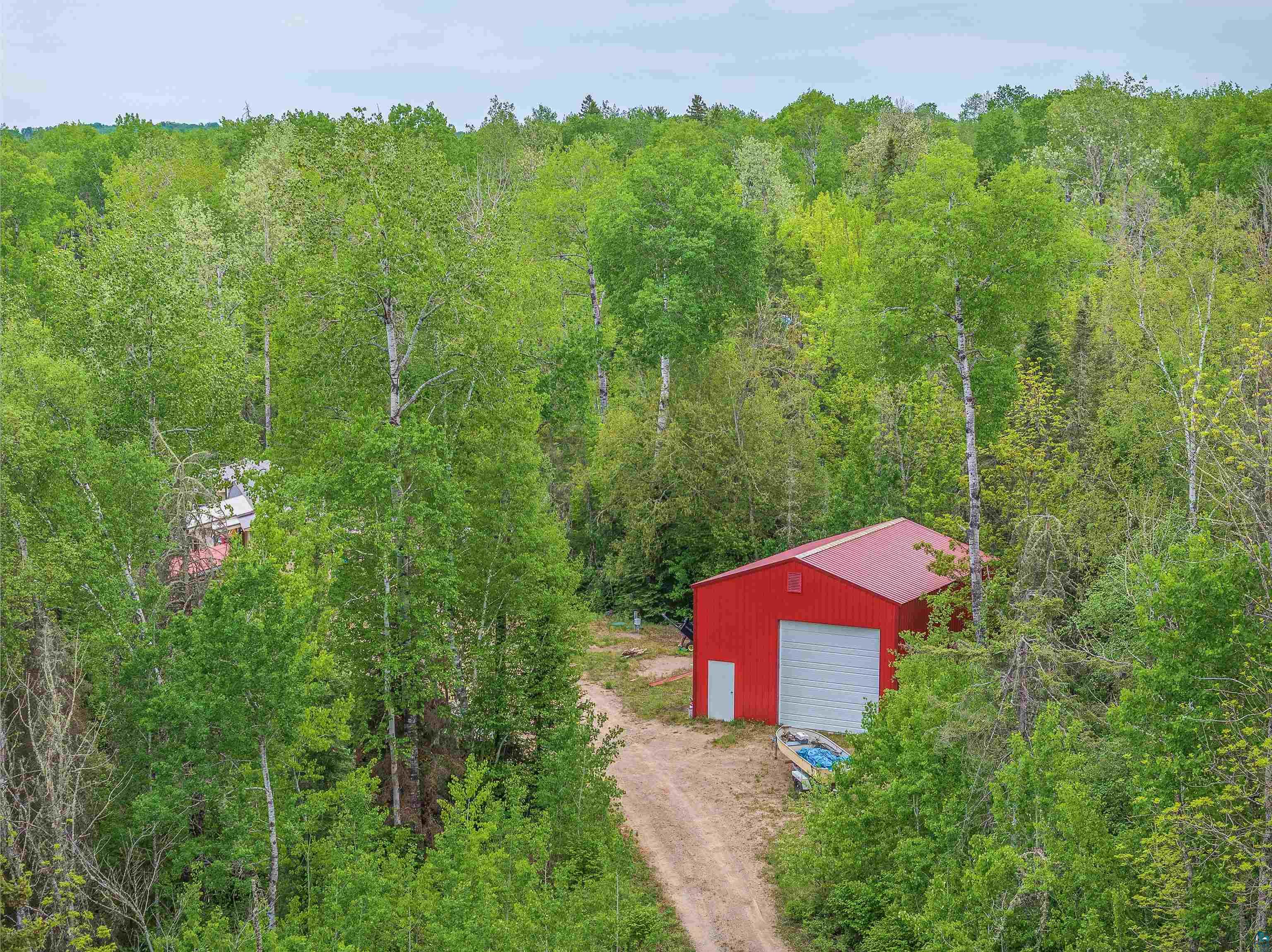 1152 Fernberg Road Ely, MN 55731 - Photo 17 of 24 Red outbuilding featuring a metal roof, white garage door, and a single entry door