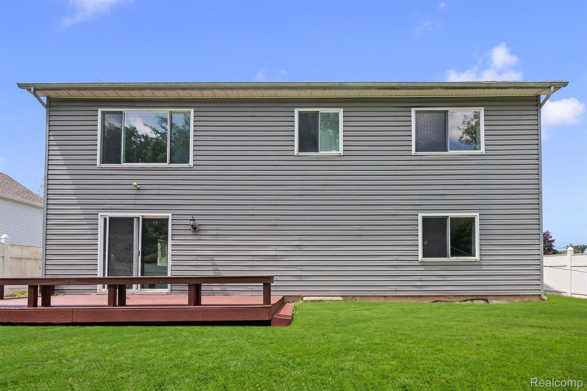 4427 Hannan Road Wayne, MI 48184 - Photo 30 of 33 Expansive wood deck with a privacy screen, gray horizontal siding, multiple windows, and a sliding glass door