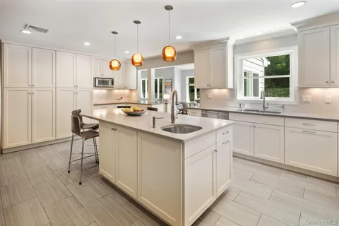 a large kitchen with a sink and chairs