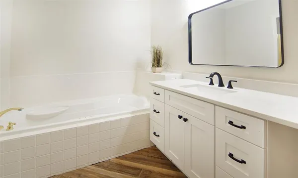 a bathroom with a bathtub sink vanity and mirror