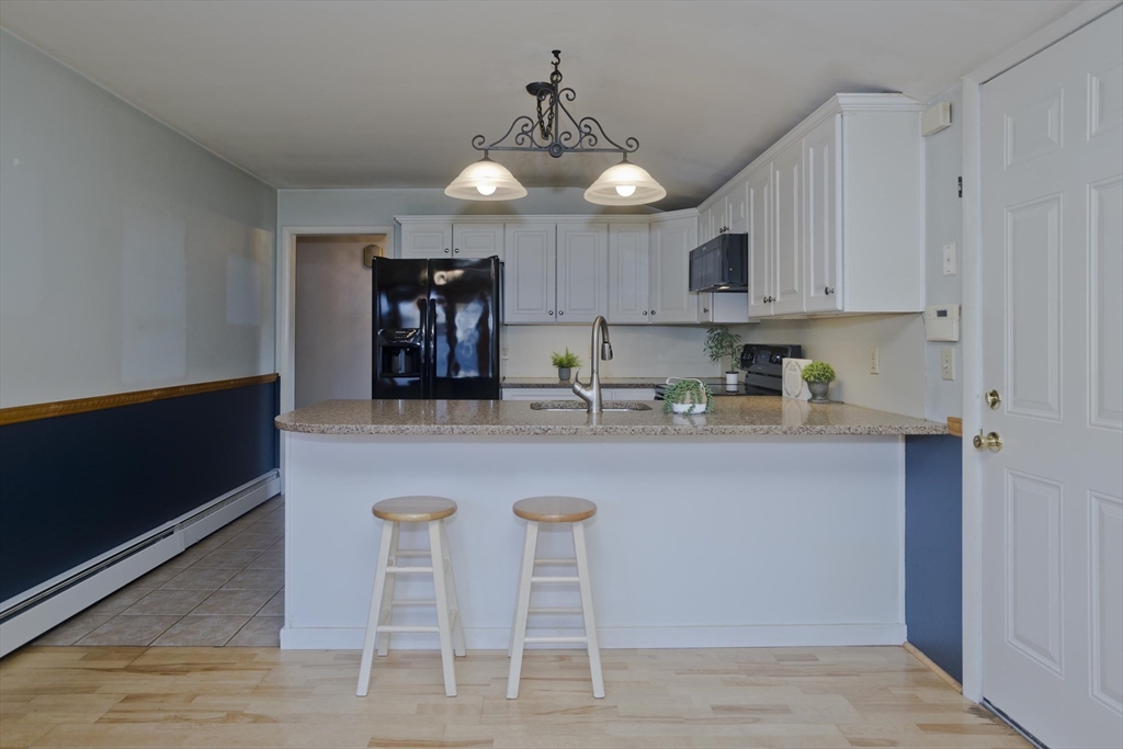 151 Bemis Road Holyoke, MA 01040 - Photo 12 of 42 a kitchen with stainless steel appliances granite countertop a stove top oven a refrigerator a sink and a dining table with wooden floor