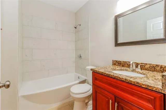 a bathroom with a granite countertop sink a toilet and bathtub