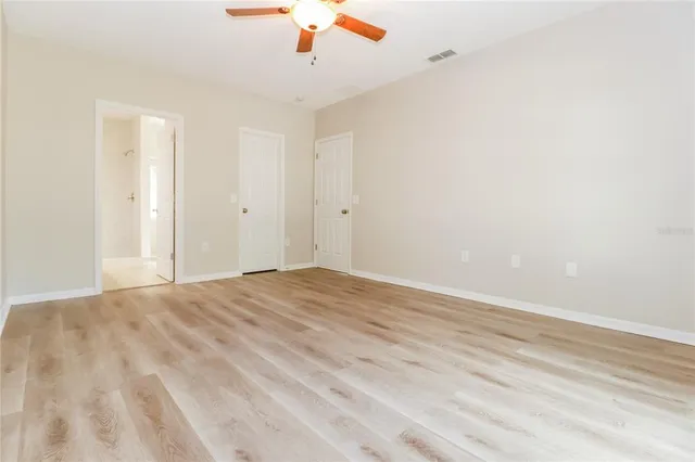 an empty room with a ceiling fan and wooden floor