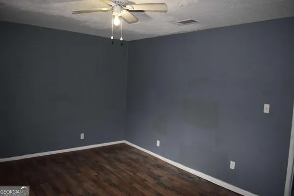 en empty room with wooden floor and fan