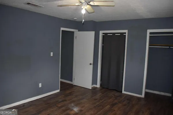 an empty room with wooden floor and closet area