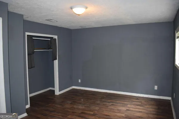 a view of an empty room with wooden floor & closet