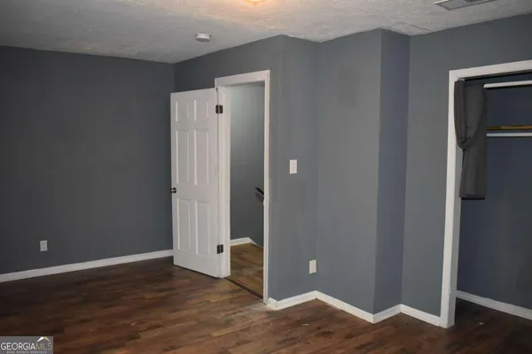 a view of an empty room with wooden floor and closet